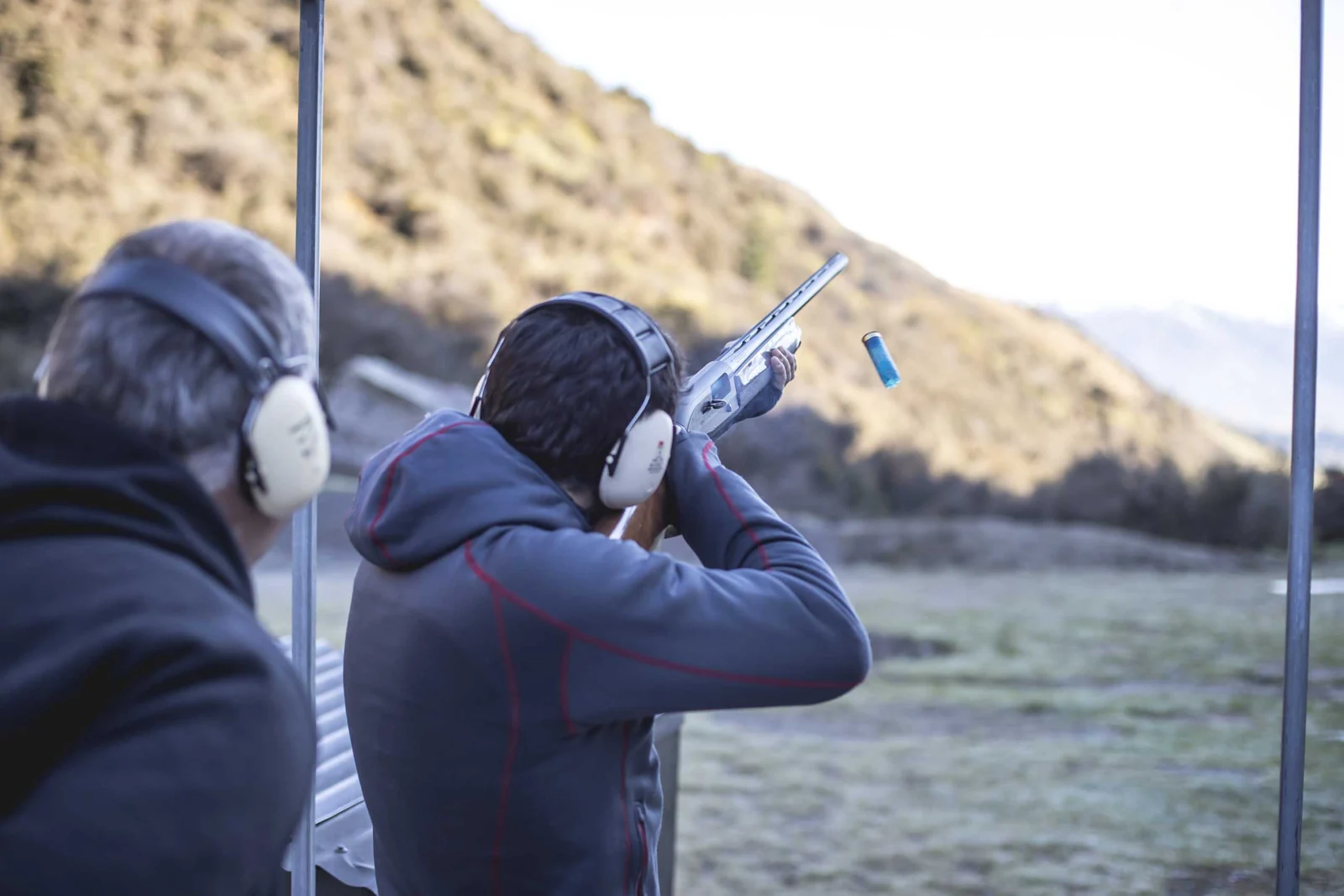 Rear view of a guest clay target shooting at BreakOne, with an instructor beside them